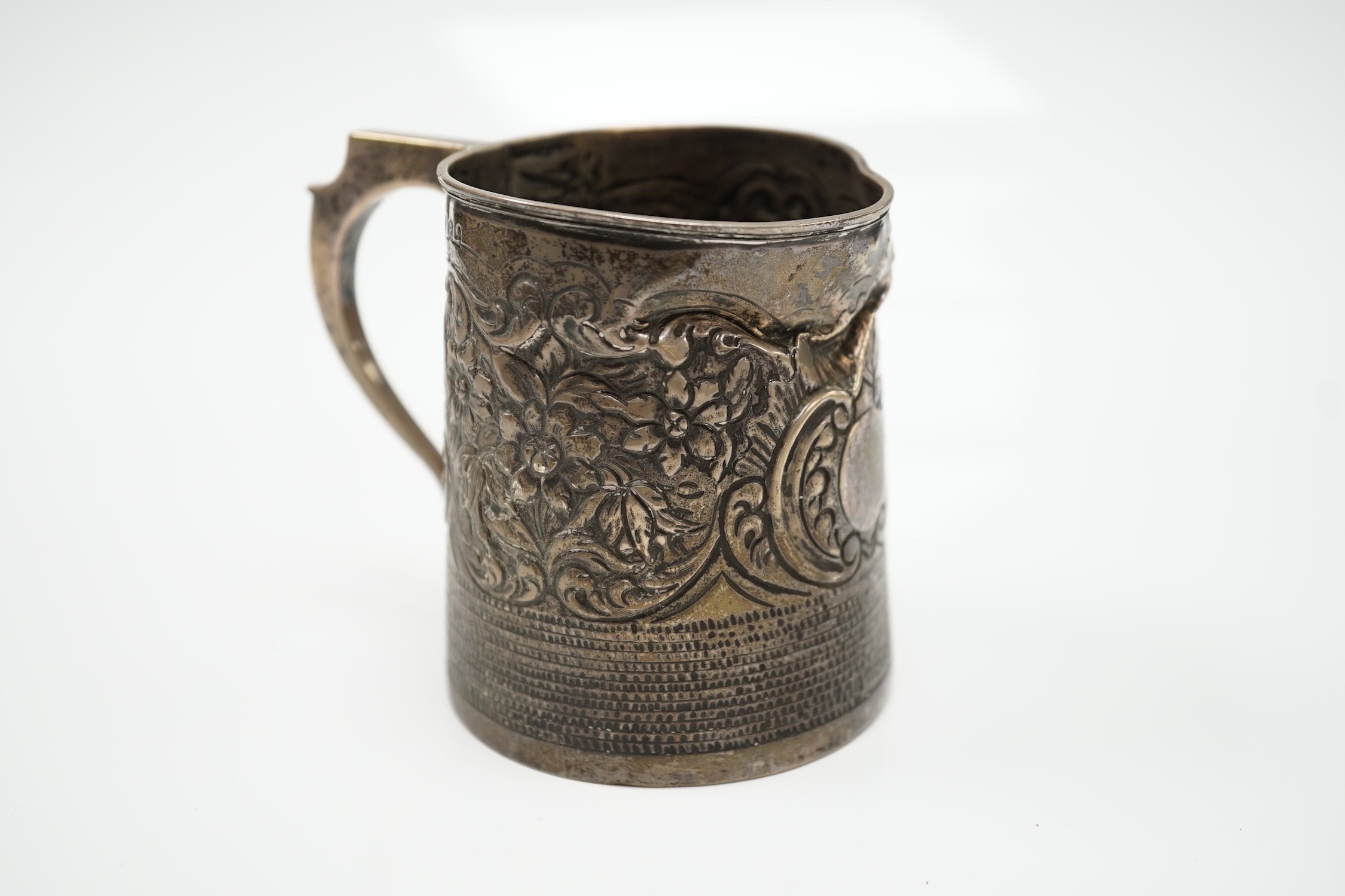A George III silver mug, with later embossed decoration (af.), Charles Hougham?, London, 1812, height 81mm.